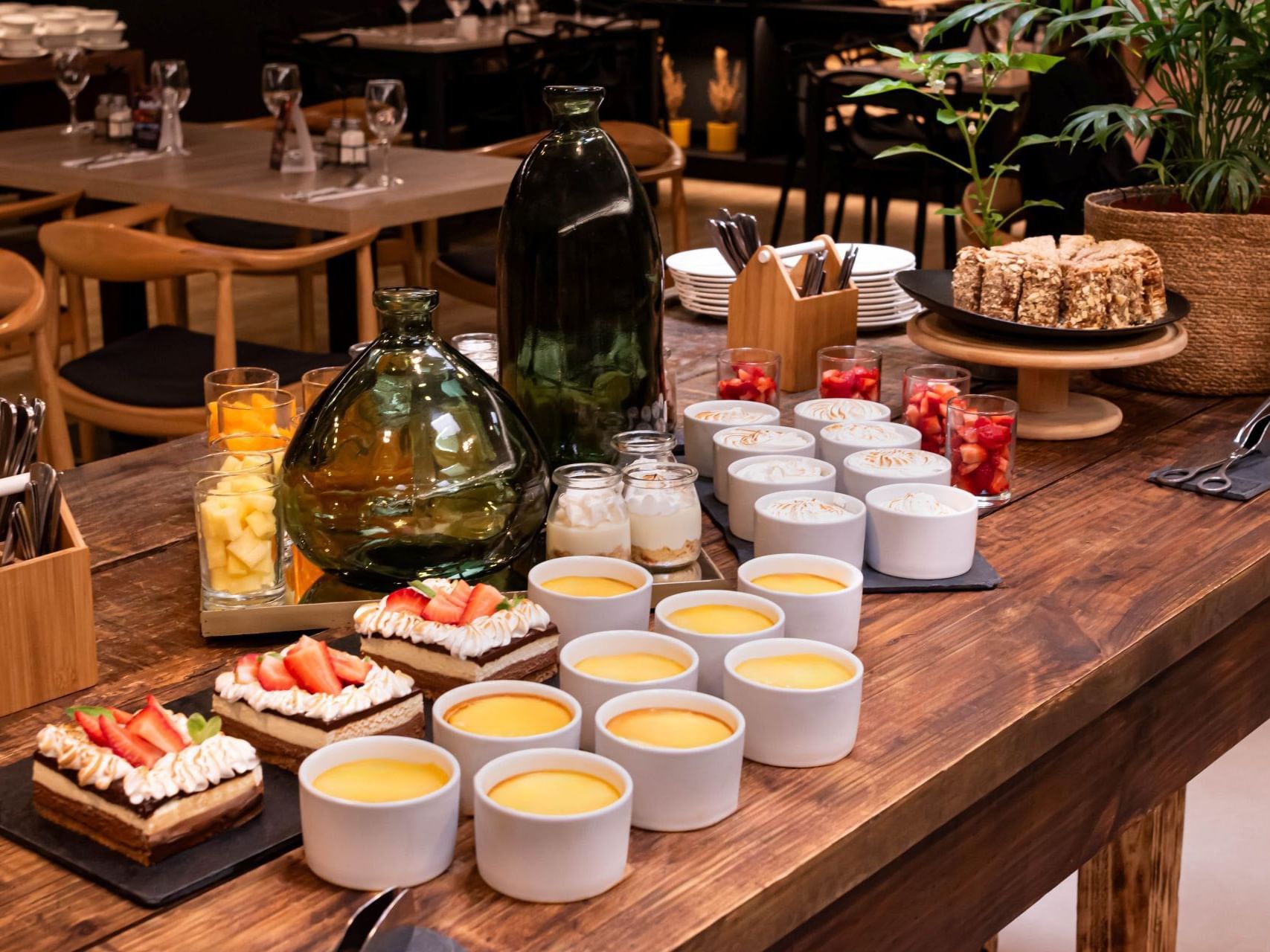 Mesa de bufé de madera con una selección de postres y bebidas en el hotel HCC Costanera Concepción.