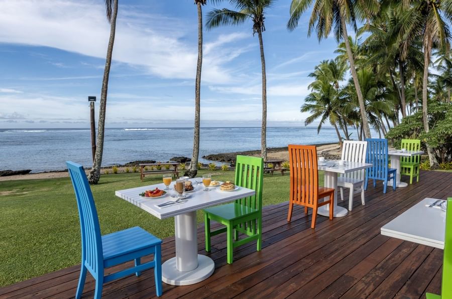 Colorful outdoor dining setup with wooden chairs and tables in Tambua Restaurant at Tambua Sands Beach Resort
