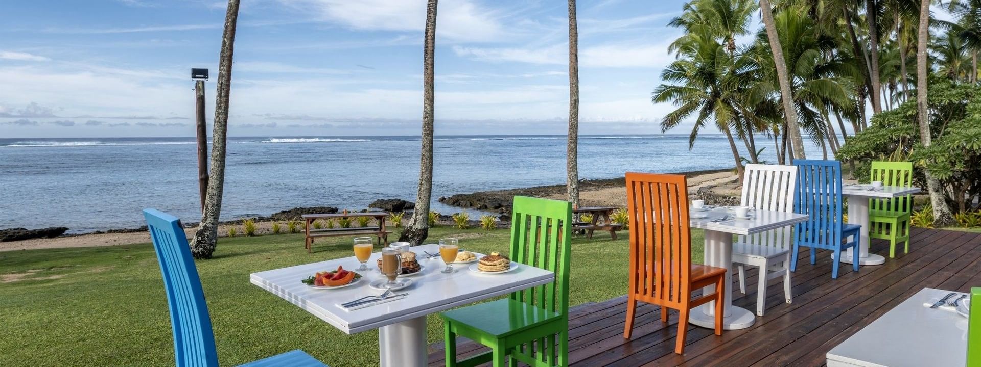Colorful outdoor dining setup with wooden chairs and tables in Tambua Restaurant at Tambua Sands Beach Resort