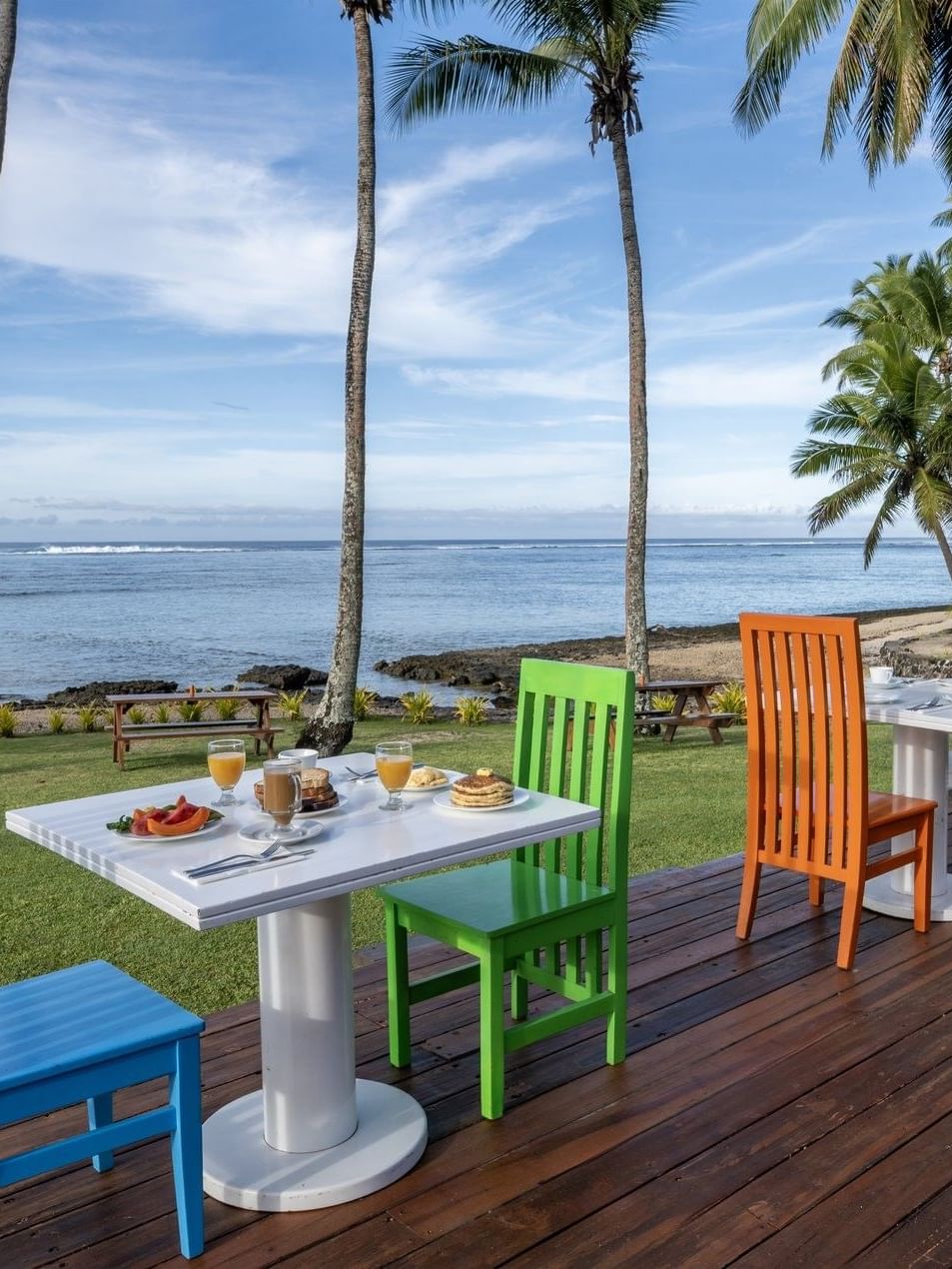 Colorful outdoor dining setup with wooden chairs and tables in Tambua Restaurant at Tambua Sands Beach Resort