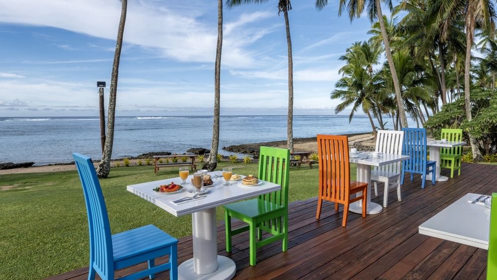 Colorful outdoor dining setup with wooden chairs and tables in Tambua Restaurant at Tambua Sands Beach Resort