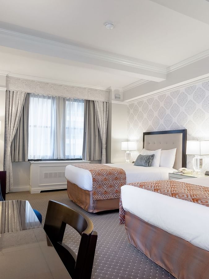 Two beds, desk, and window in Premier City View room at Warwick New York.