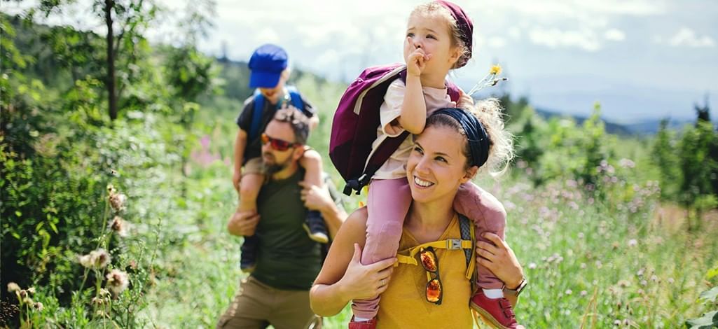 Parents hoist their kids on their shoulders during a hike in Canmore on a sunny summer day.