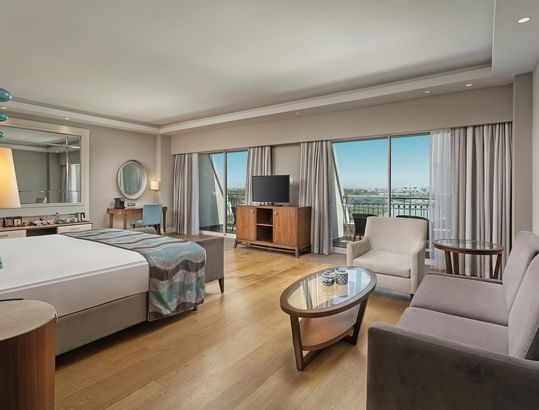 TV & lounge area by the bed in Deluxe Suite with wooden floors at Titanic Deluxe Golf Belek