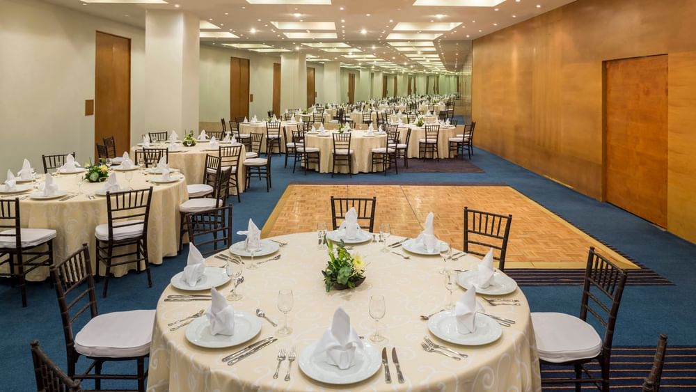 Banquet set-up with floral centerpieces and carpeted floors in the CDMX Venue at Real Inn San Luis Potosi