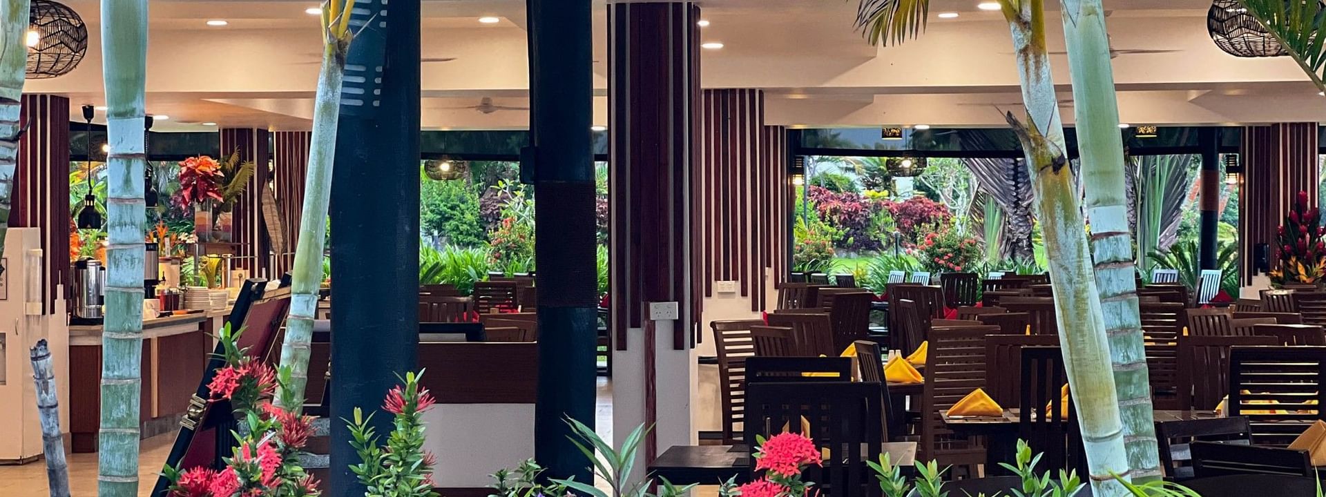 Outdoor dining area with tables, chairs, and tropical plants at Nukunuku Restaurant & Bar in Korolevu, Fiji