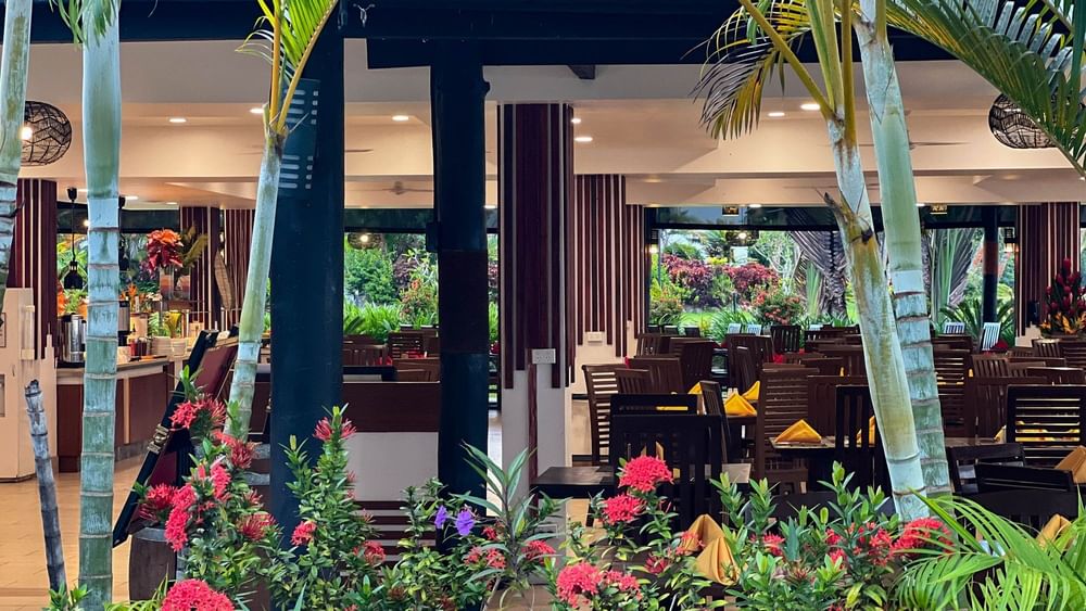 Outdoor dining area with tables, chairs, and tropical plants at Nukunuku Restaurant & Bar in Korolevu, Fiji.