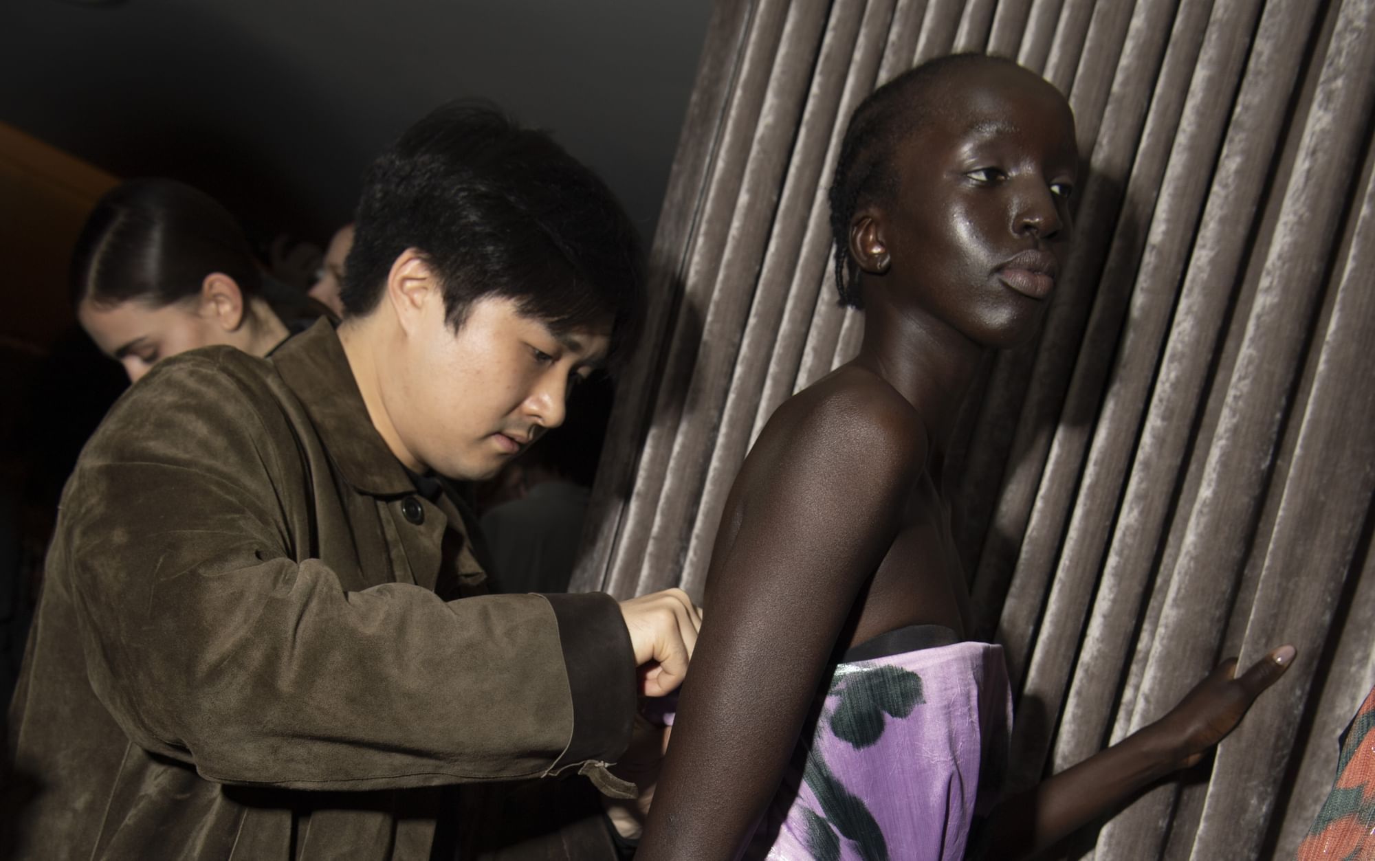 Designer adjusts model’s purple gown backstage at Huishan Zhang fashion event near The Londoner