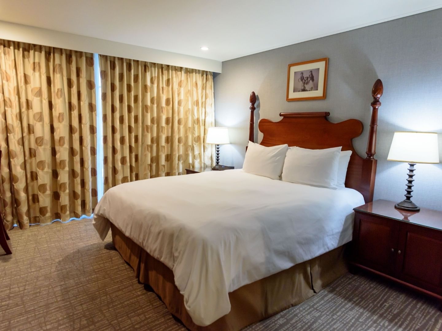 Studio 1 King with wooden four-poster bed, patterned curtains, and bedside lamps at Polynesian Residences, Honolulu