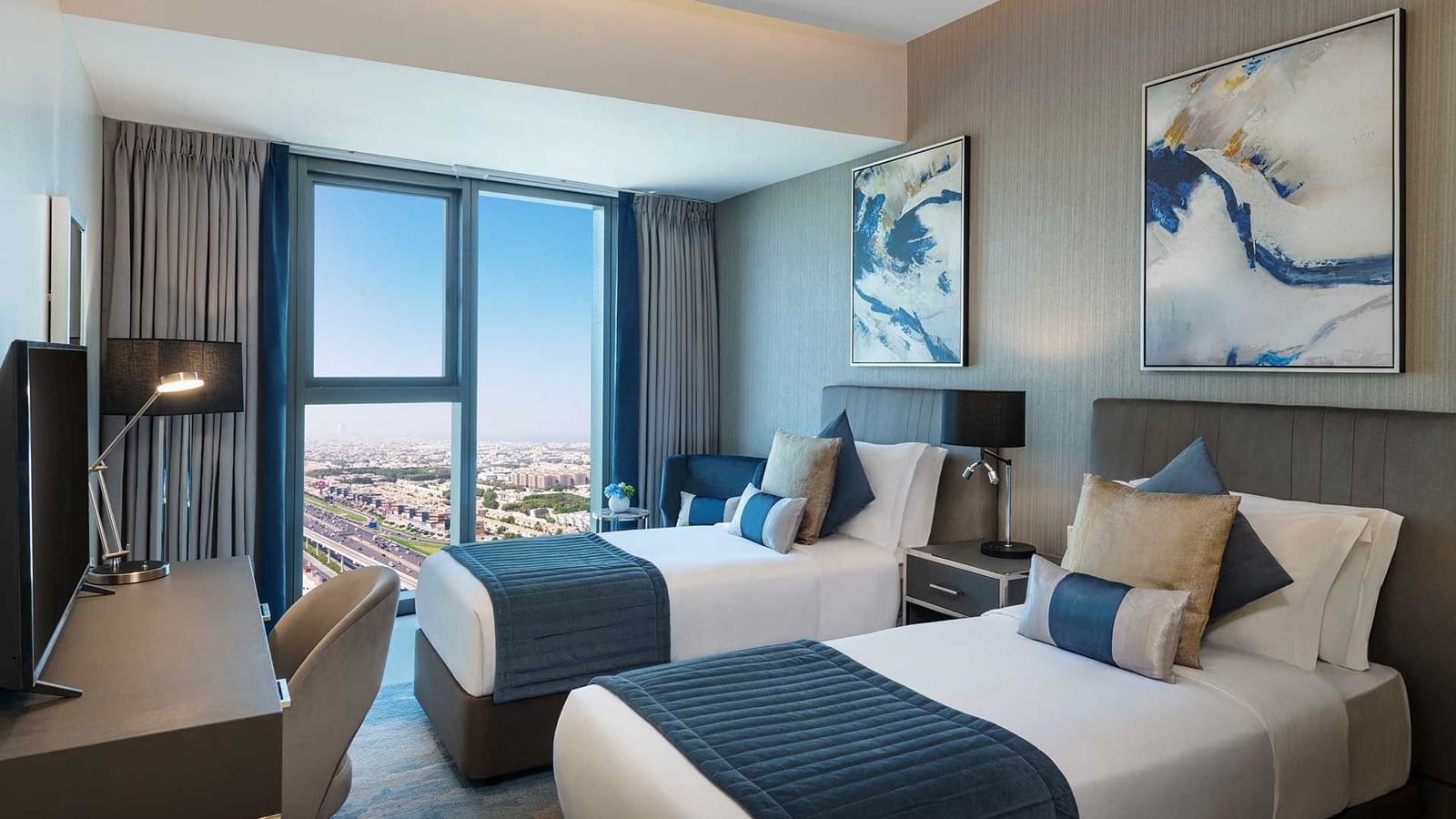 Work desk facing the twin beds in a room with a city view at DAMAC Maison Aykon City