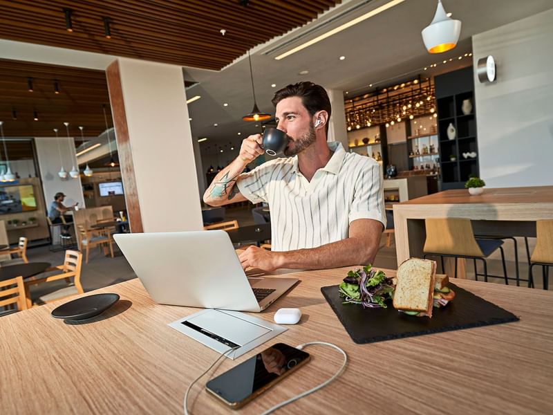 Man sipping on coffee while working at IOH Freestyle Hotels