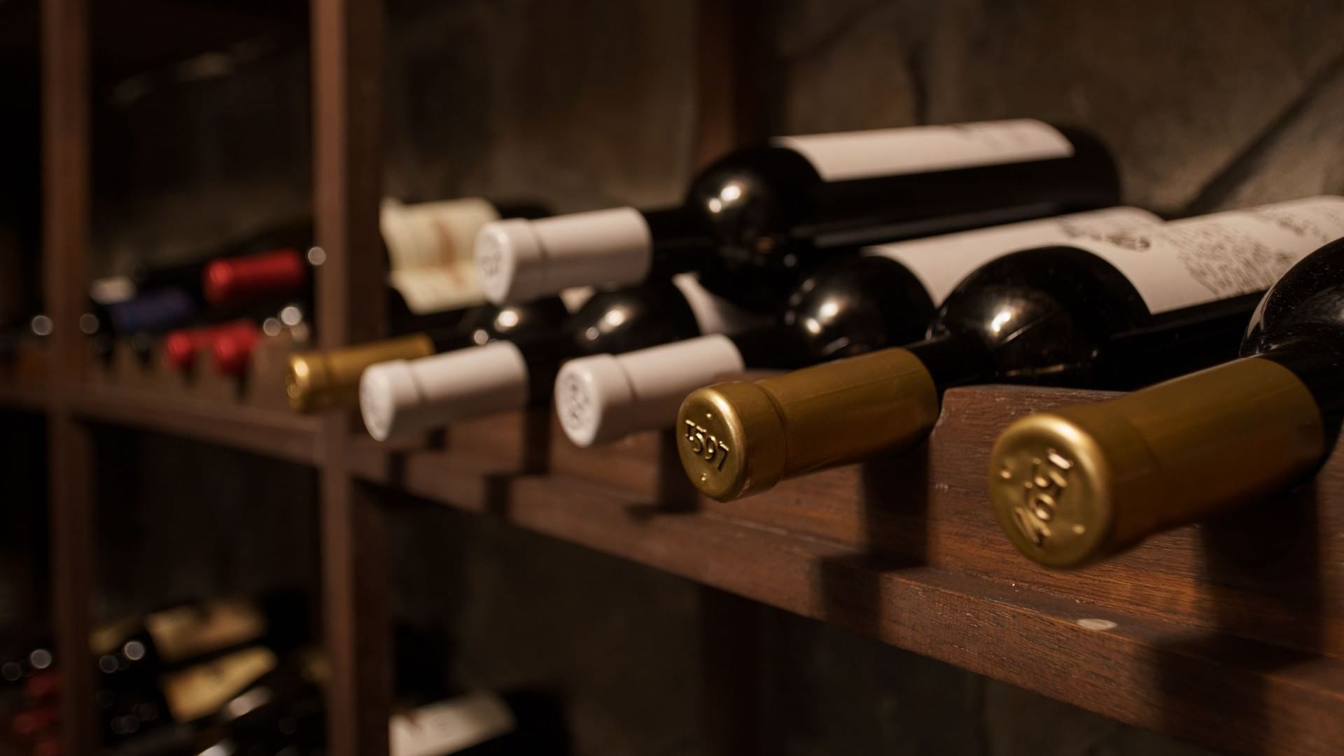Rack of red wine bottles with white and gold caps in a wine cellar at La Cava de Santiago in Hacienda del Mar Los Cabos.