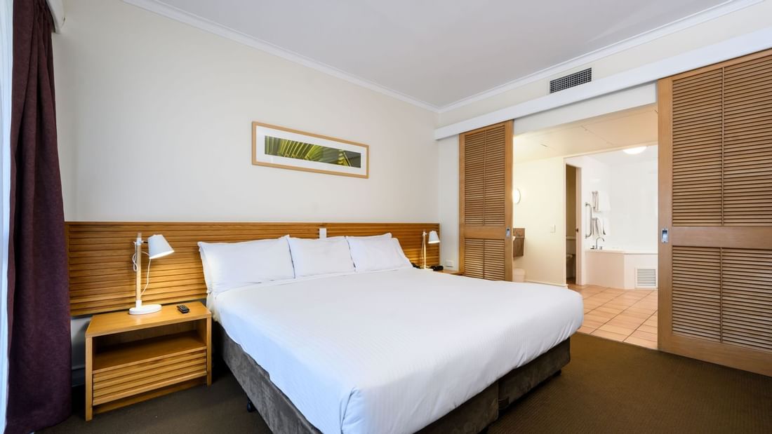 Bed with nightlamps by bathroom vanity in One & Two-Bedroom Suites at Novotel Sunshine Coast Resort