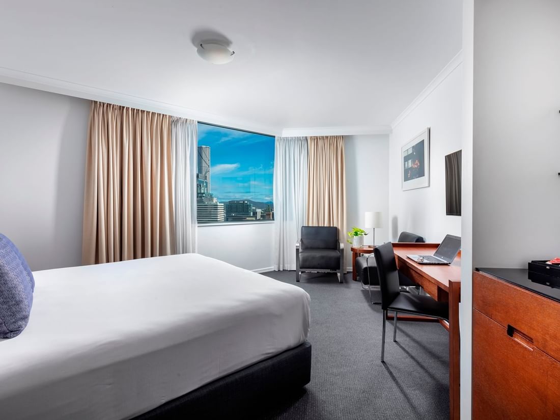 Premium Studio Room featuring a city skyline, desk area, seating chair, and clean white bedding at The Sebel Brisbane