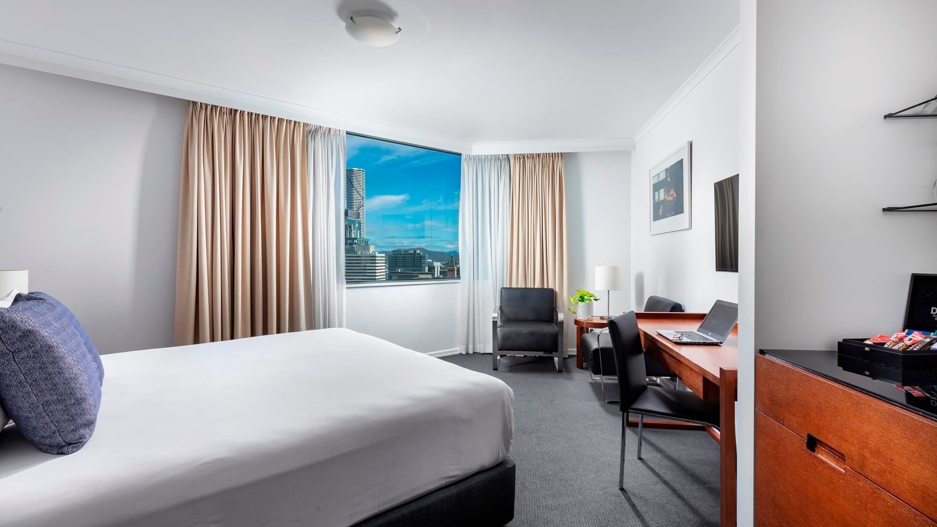 Premium Studio Room featuring a city skyline, desk area, seating chair, and clean white bedding at The Sebel Brisbane