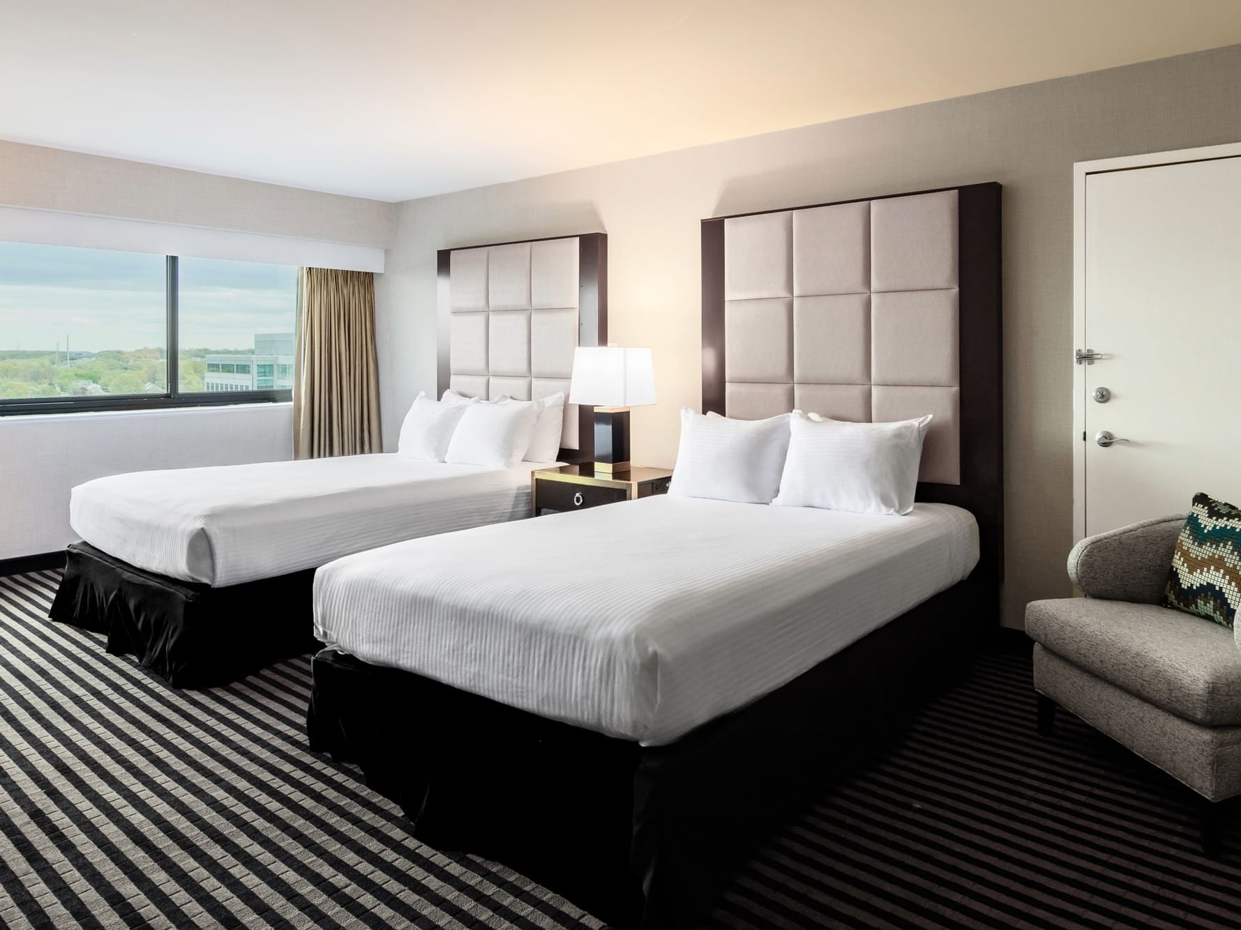 Superior room with two queen beds and striped carpet at APA Hotel Woodbridge, Iselin.