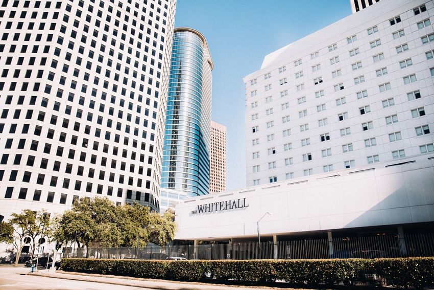 Exterior of The Whitehall Houston featuring its signage amid downtown Houston’s modern architecture