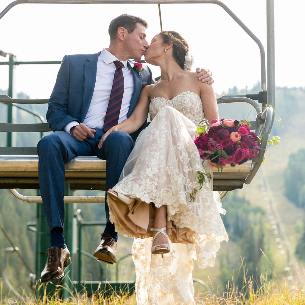 A bride and groom kissing on a ski lift at Stein Lodge