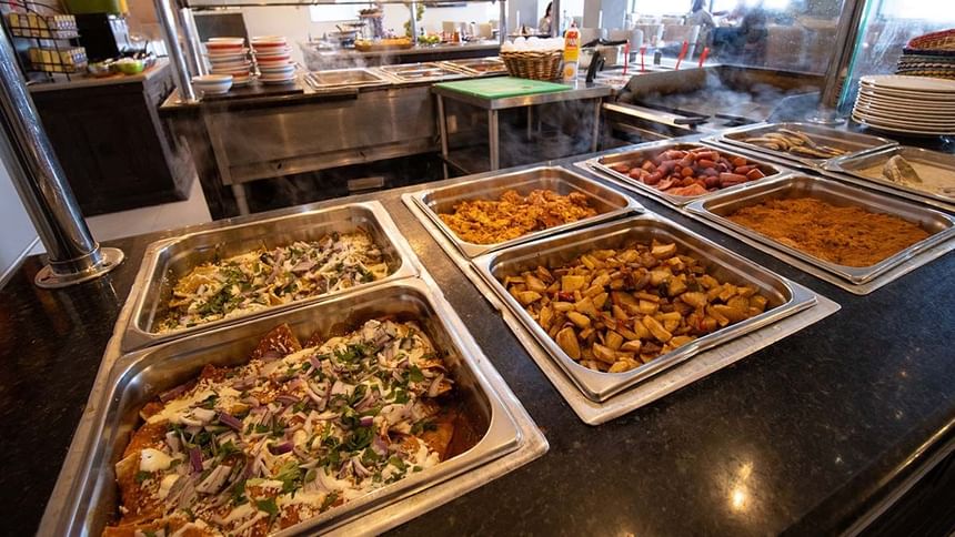 Steam trays of chilaquiles and breakfast potatoes at a hot breakfast buffet in Palmira Cafeteria at Araiza Calafia