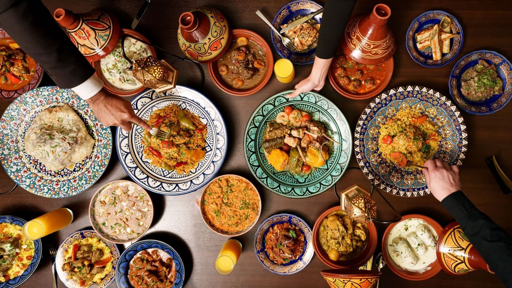 Overhead view of a table filled with colorful Moroccan dishes and people eating at Paramount Hotel Dubai