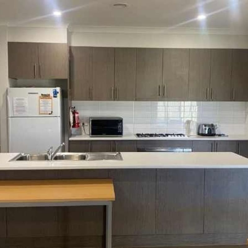 Modern kitchen with white appliances, gray cabinets, and white counters in La Trobe University Regional Housing – Mildura.