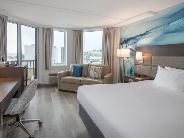 Coast Accessible King room with a large bed, sofa, desk, and balcony at Coast Bastion Hotel in Nanaimo.