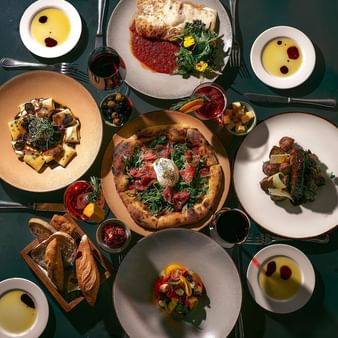 A table full of delicious gourmet Italian food, including pizza, pasta, and appetizers at Hacienda del Mar Los Cabos