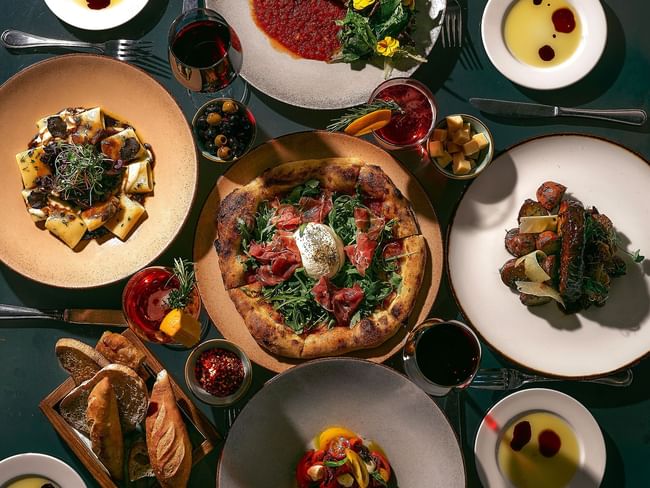 Una mesa llena de deliciosa comida italiana gourmet, que incluye pizza, pasta y aperitivos en Hacienda del Mar Los Cabos