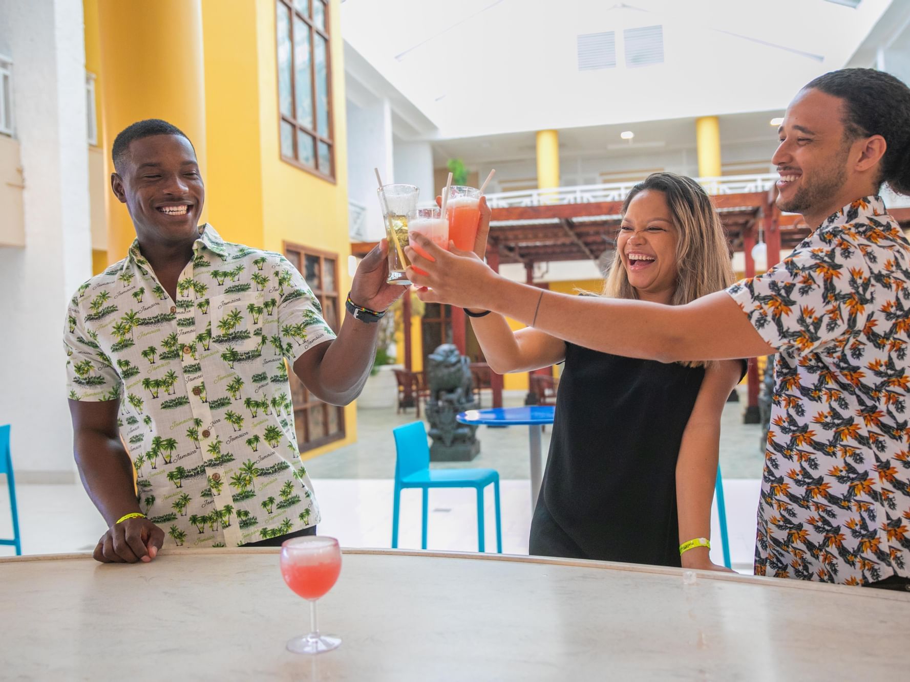 Three people toasting cocktails in De Lobby Bar at Holiday Inn Montego Bay