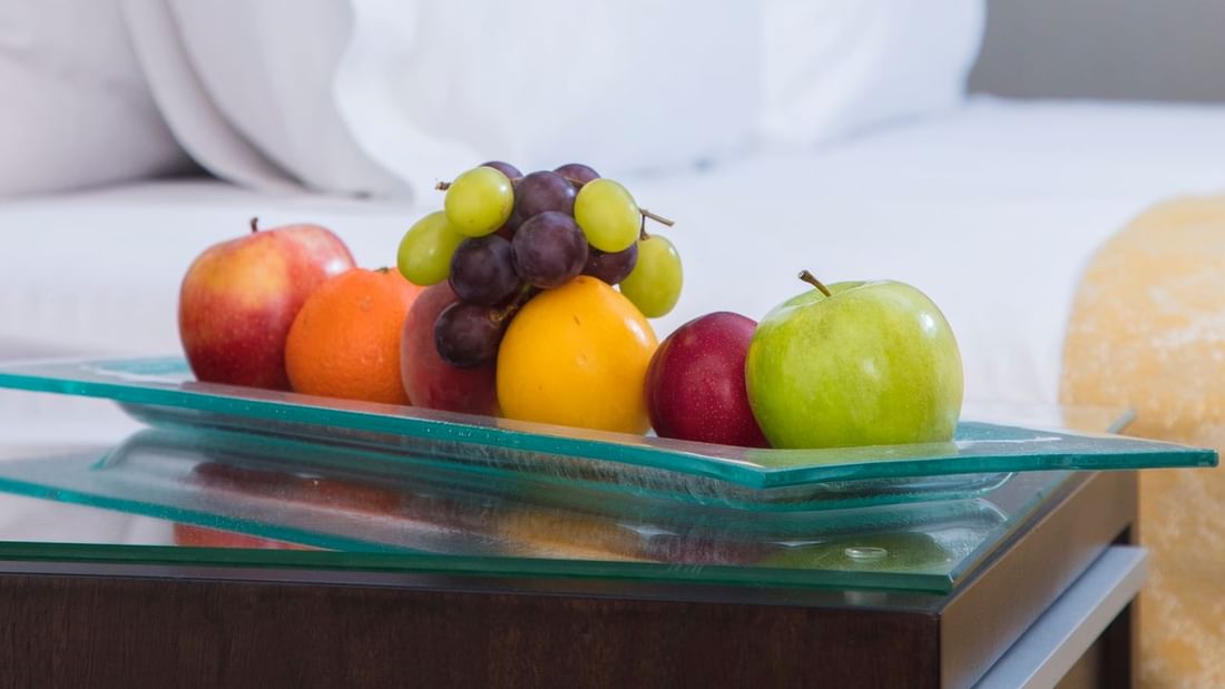 Colorful assortment of fruits arranged on a glass plate on a bedside table in the Superior Room at Warwick Hotel Jeddah
