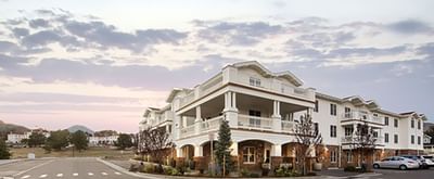A beautiful multi-story white building with columns and balconies at The Stanley Hotel, with a wide driveway and trees