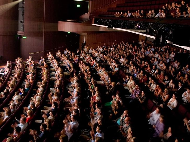 Audience seated in a modern theater auditorium with multiple levels during a performance at QPAC