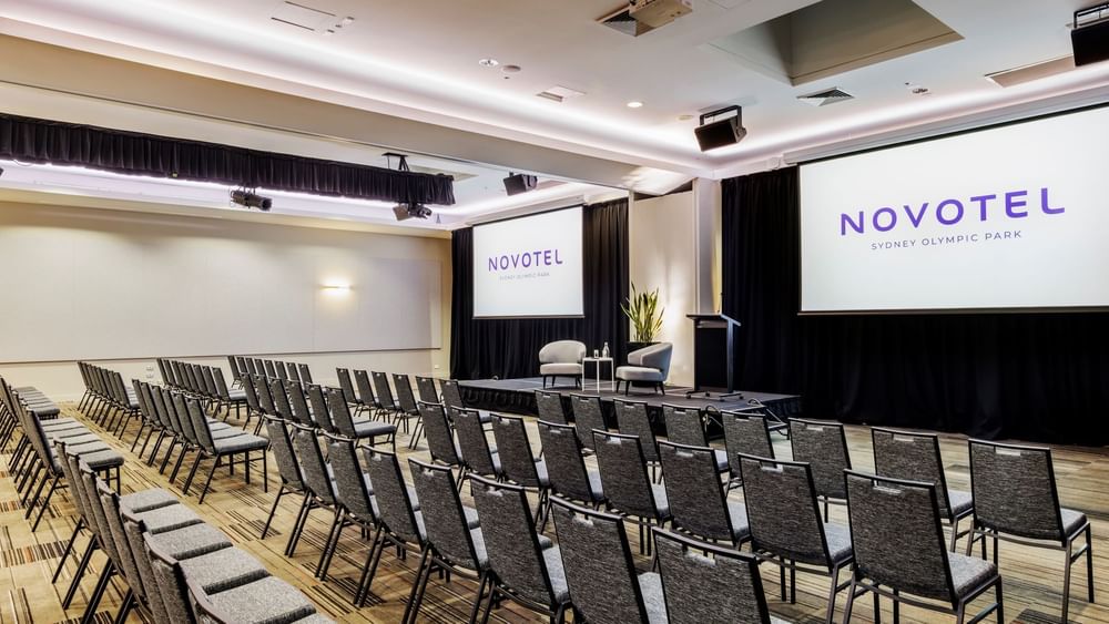 Theatre set-up with presentation area and screens in Freshwater Ballroom at Novotel Sydney Olympic Park