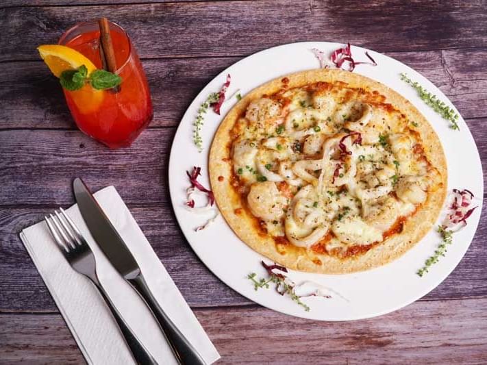 A pizza served with a cocktail at Maitria Hotels & Residences