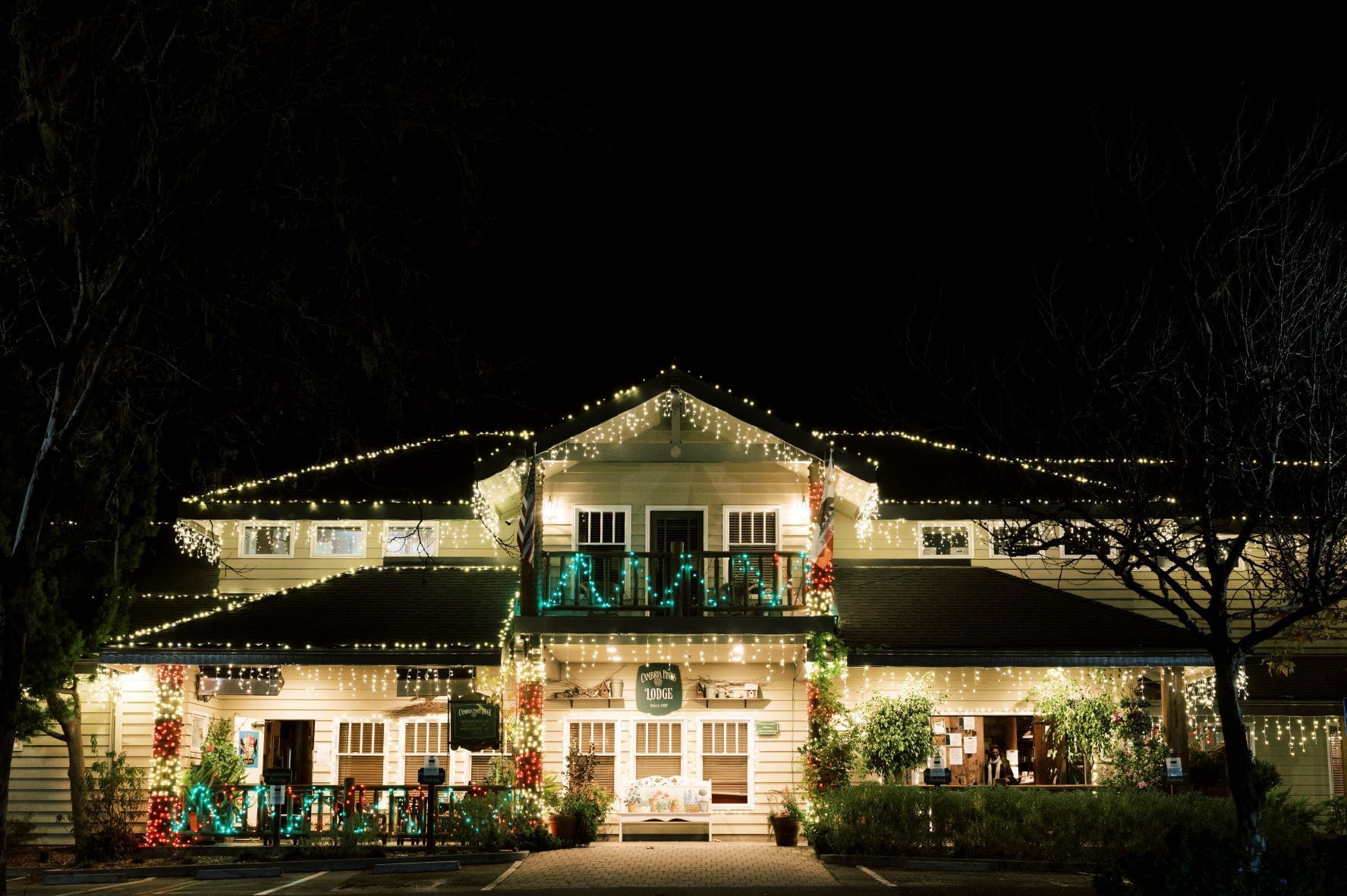 A two-story building with Christmas lights on the exterior at night.
