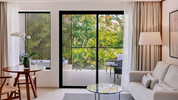 Living area with arranged seating and carpeted floors in Premium Garden View room at Live Aqua Punta Cana