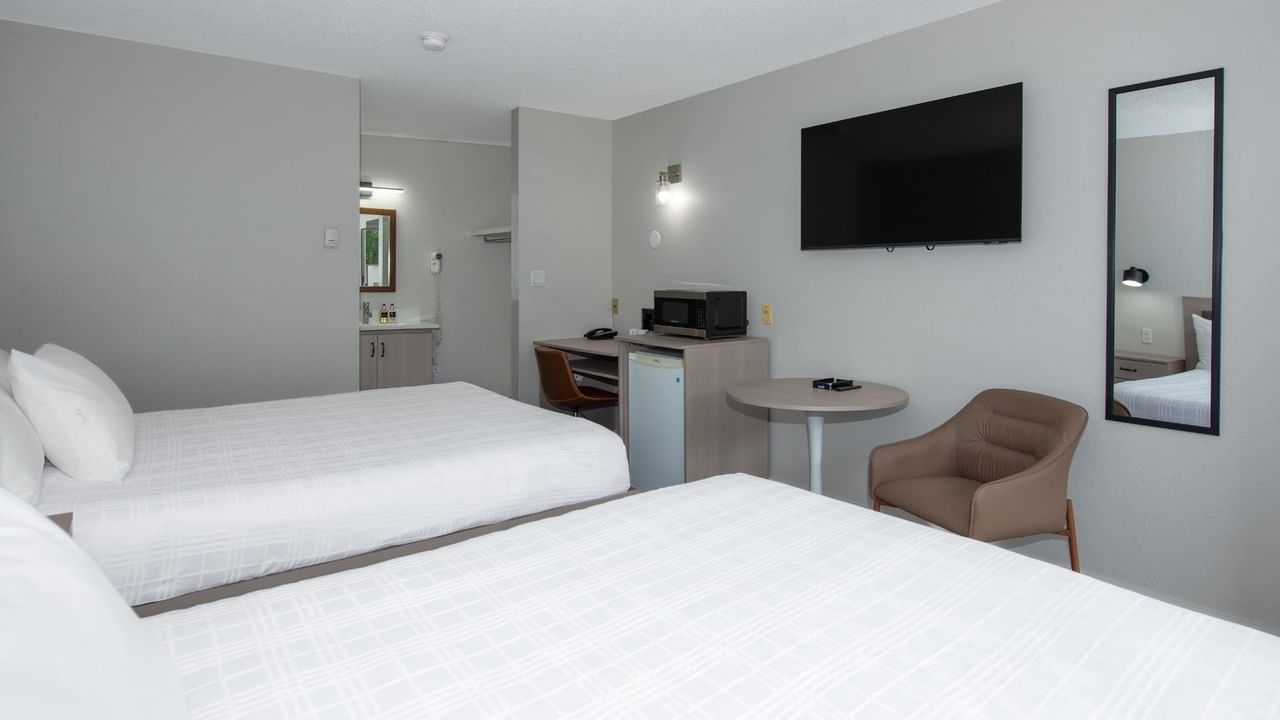 Two queen beds and seating area in a guest room at Coast Red Deer Hotel