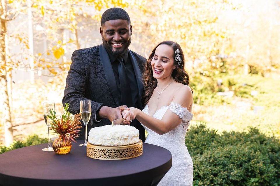 Bride and groom cutting a cake together in outdoor wedding reception in The Study at University of Chicago