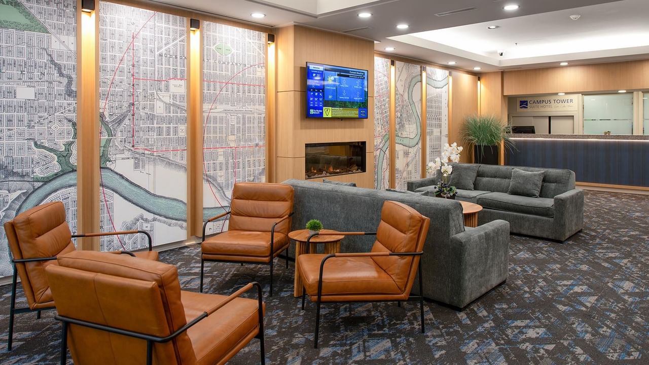 Hotel lobby lounge with leather armchairs, sofas and a wall-mounted TV.