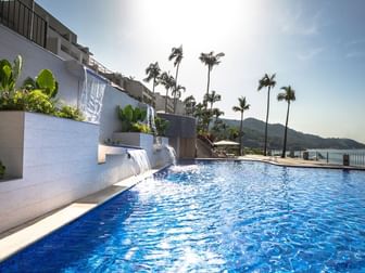 Luxury outdoor infinity pool with waterfalls, palm trees, and ocean views at Camino Real Acapulco Diamante