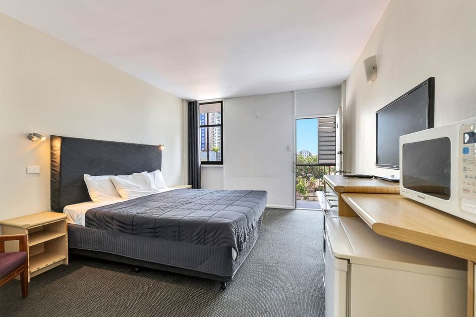 TV facing Bed and balcony area in the King Room, one of Darwin CBD Accommodation at Darwin Poinciana Inn