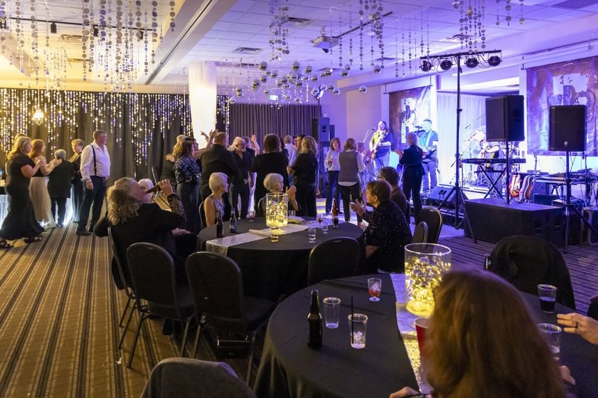 Guests socializing by round tables under hanging decorations, with a live stag at Rodd Miramichi River