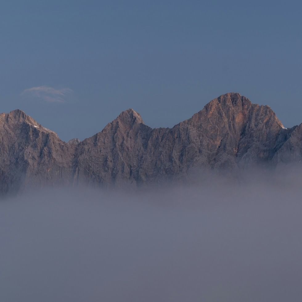 Majestätische Berggipfel des Hohen Dachsteins ragen aus dichtem Nebel im Morgenlicht empor