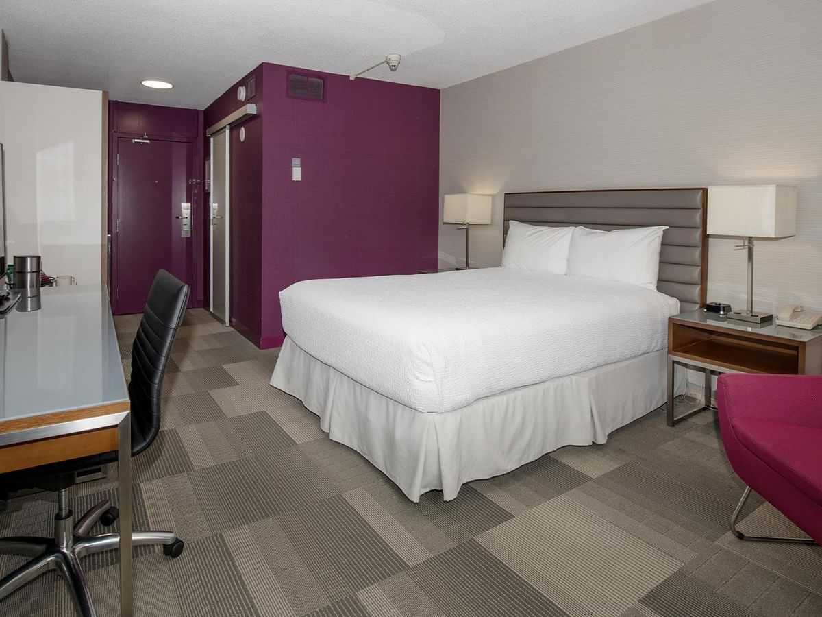 Coast Queen room with white bedding, purple accent wall, work desk, and modern furnishings at Coast Prince George Hotel