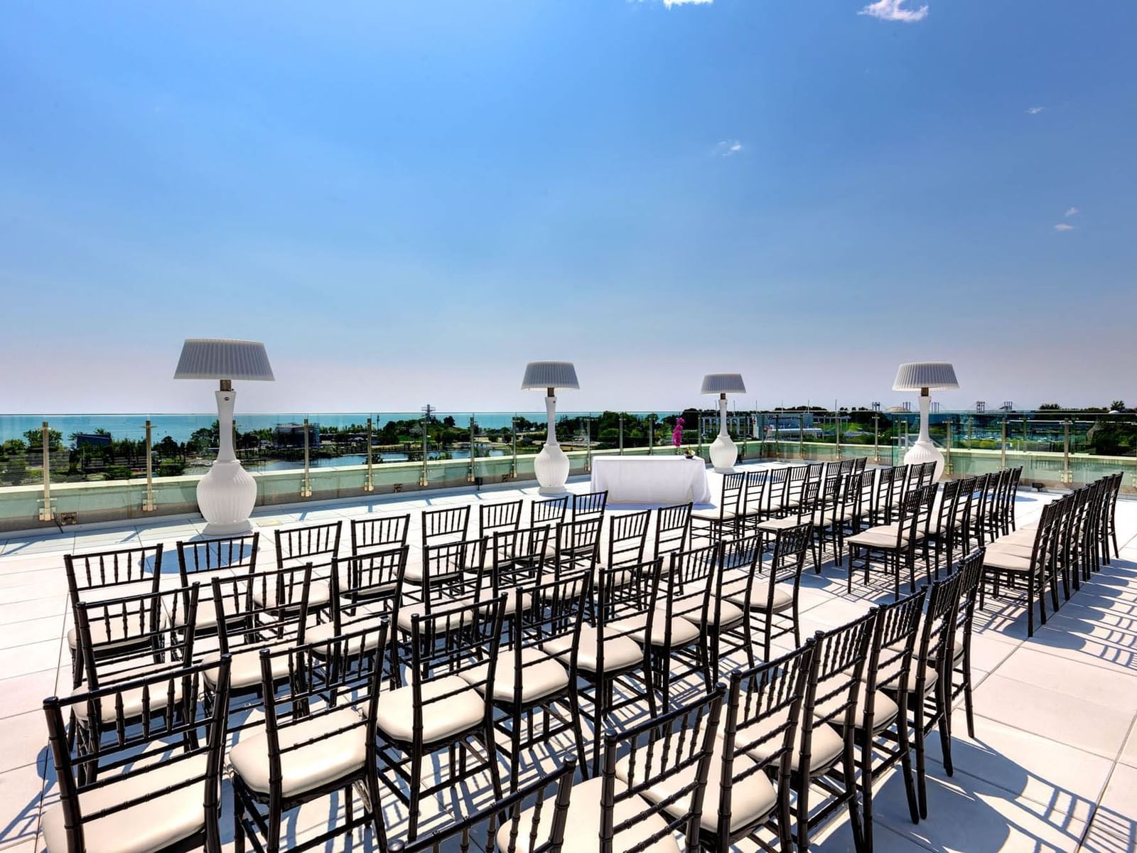 Outdoor event setup with rows of chairs and large lamps overlooking a beach in High Park Terrace at Hotel X Toronto