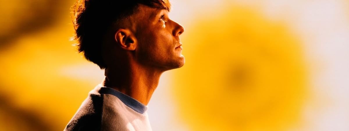 Louis Tomlinson looking upward with yellow sunburst background for the How Did We Get Here Tour 2026.