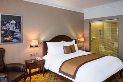 Club Deluxe Room with a king sized bed & a comfy chair at Eastin Grand Hotel Saigon