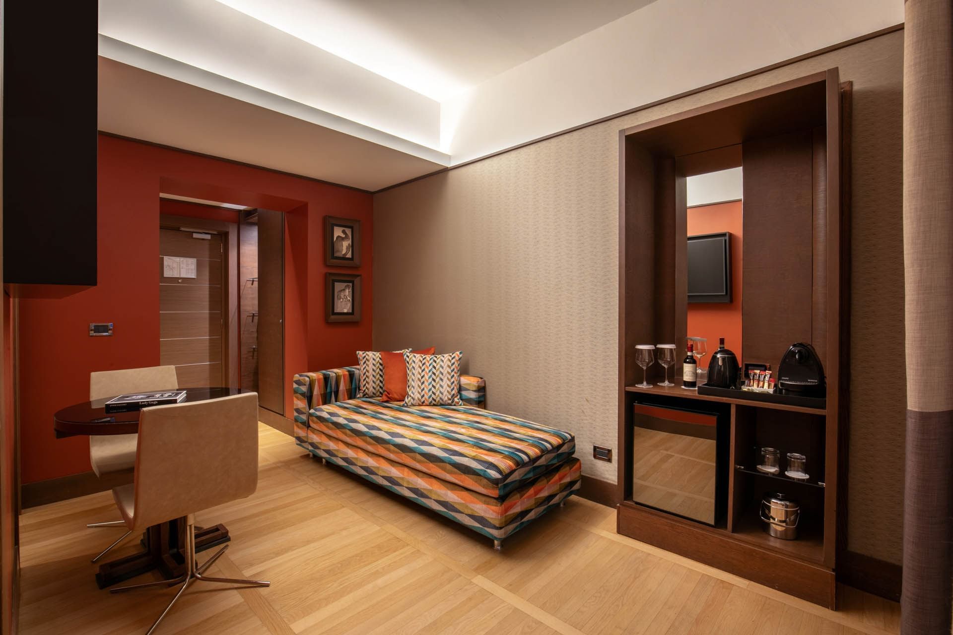 Modern Junior Suite at The Independent with colorful striped couch, round dining table, and beverage station