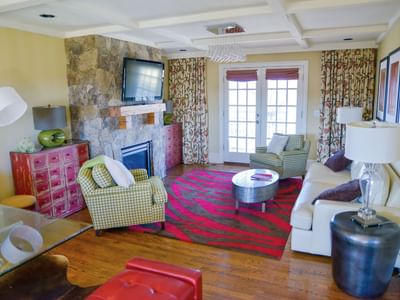 The Overlook West living room with eclectic furniture and a stone fireplace at the inn at Willow grove