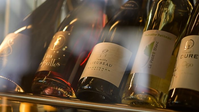 Plusieurs bouteilles de vin sont alignées sur une étagère à Hôtel Rivella.